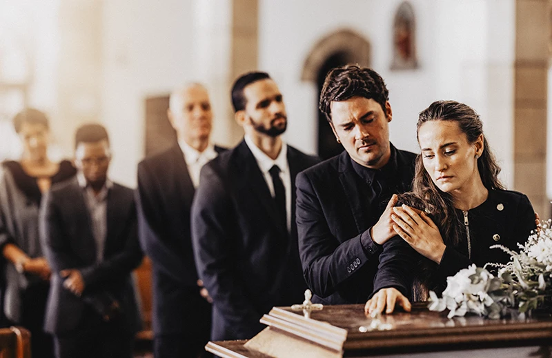 Trauerfotografie Rastatt Baden-Baden. Trauergäste am Sarg bei einer Trauerfeier.