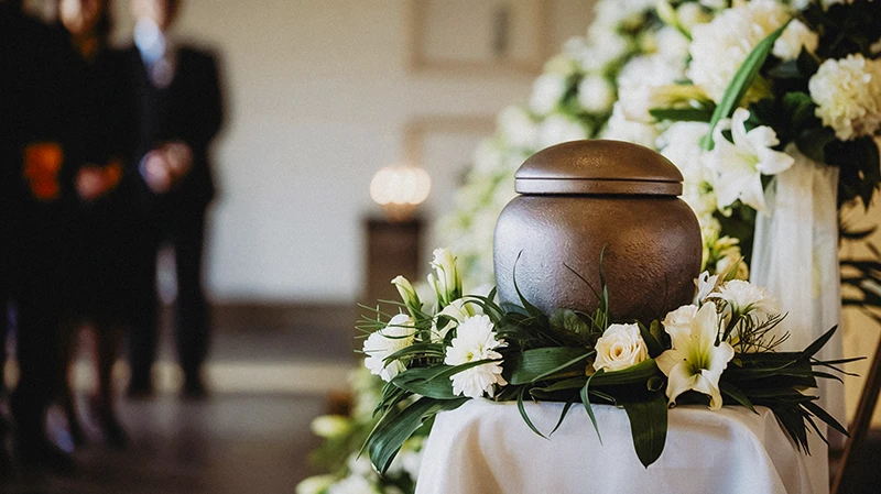 Trauerfotografie Rastatt Baden-Baden. Urne mit Blumenschmuck bei einer Trauerfeier.