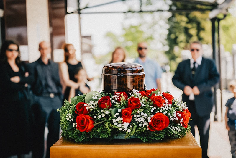 Trauerfotografie Rastatt Baden-Baden. Trauergäste an einer Urne bei einer Trauerfeier.